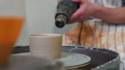 Potter dries a craft cup with a const ruction hair dryer Vidéo 162811788