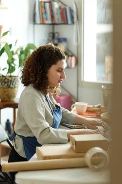 Potter entrepreneur using laptop in workshop, smiling Stock Photos