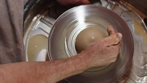 Potter gives round shape to future pottery with two hands, using potter's wheel Stock Footage 158697103