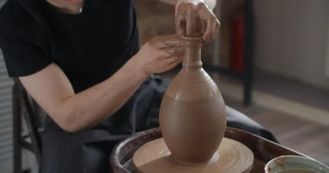 Potter makes a jug's neck in slow motion on a potter's wheel, video from pottery Stock Footage 150819909