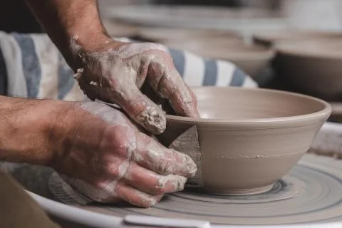Potter making a bowl of white clay on the potter's wheel circle in studio, co 库存照片