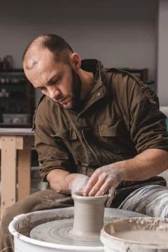 Potter making a jar pot of white clay on the potter's wheel circle in studio, Photos
