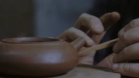 A potter marking the base of a clay teapot for attaching a spout for a teapot Stock Footage 119537645