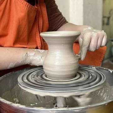 Potter modeling ceramic pot from clay on a potter's wheel.  The woman's hands Stock Photos