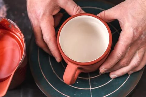 Potter or decorator examining after painting red color of the ceramic clay cu Photos