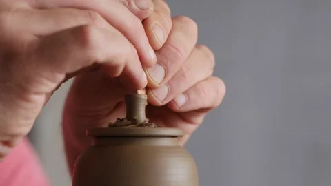 Potter removing excess clay from the handle of the lid of  clay teapot Stock Footage 145543850
