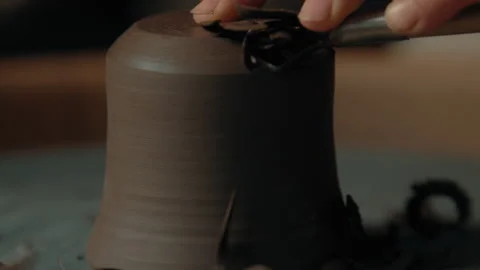 Potter scrapes and smooths base on cup with scraping tool Stock Footage 275086371