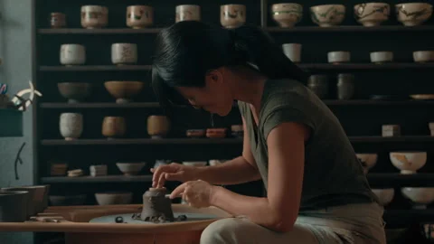 Potter scrapes base sides of cup on pottery wheel in studio Stock Footage 275086048