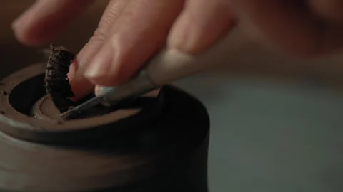 Potter scraping clay cup foot as it spins on pottery wheel Stock Footage 275085953
