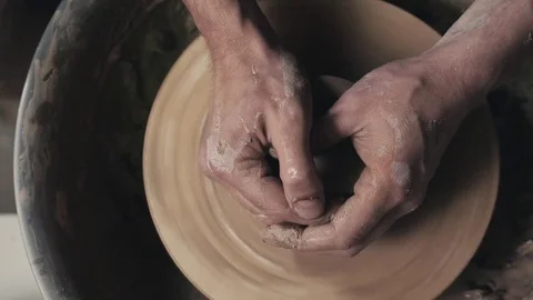 Potter shapes the clay product with pottery tools on the potter's wheel, top Stock Footage