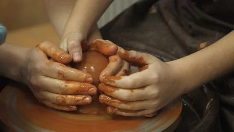 A potter shows how to properly hold a piece of clay on a potter's wheel. 動画素材 148877129