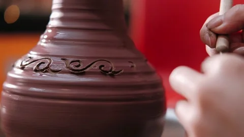 Potter uses ribbon tool with which makes pattern on clay vase, closeup Stock Footage 228731341
