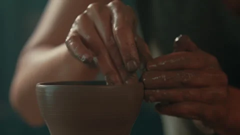 Potter using fingers to smooth sides and rim of clay bowl on pottery wheel Stock Footage 275086568