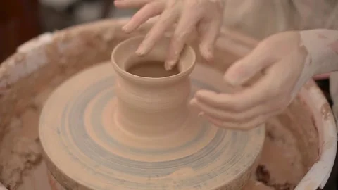 A potter is using his finger to shape a clay pot rotating on a potter's wheel Stock Footage 143807931