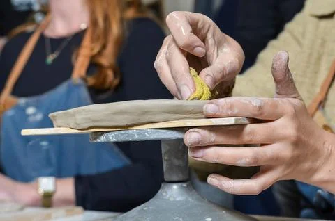 Potter using sponge to smooth clay on pottery wheel Stock Photos