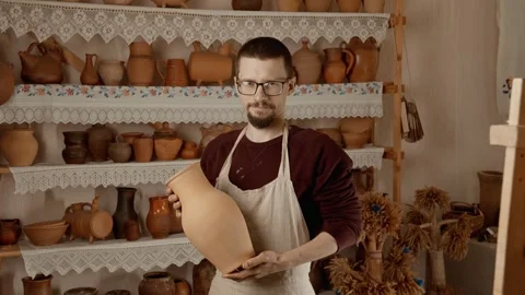 Potter with vase in hands looking at camera. Portrait of young craftsman Video stock 245156864
