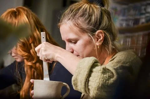 Potter working clay in pottery workshop with wooden tool Stock Photos