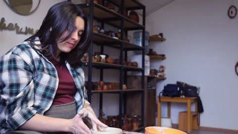 Potter's apprentice tries to make smooth edges at a clay cup on a potter's wheel Video stock 165554265
