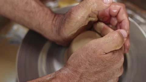 Potter's hands add liquid to clay with their and fingers form rounded shape Stock Footage 158475194