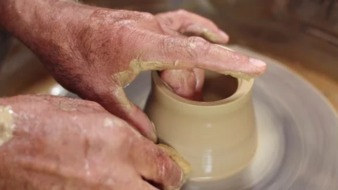 Potter's hands hold clay jug on potter's wheel and give it smooth shape with wet Stock Footage 157688983