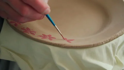 A potter's hands paint a ceramic plate with a brush. Close up Vidéo 234847647