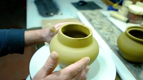 Potter's hands shaping a raw clay pot on a rotating wheel. Stock Footage 328925155