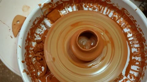 A potter's wheel with an orange clay jug is rotating (top view) Stock Footage 148181237