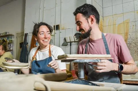 Potters working with clay smiling at each other in workshop Stock Photos