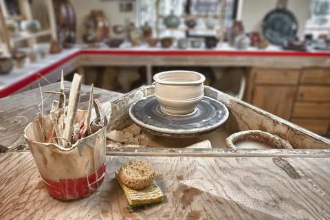 A potter's workshop, a potters wheel, working tools and sponges on a board,.. Stock Photos