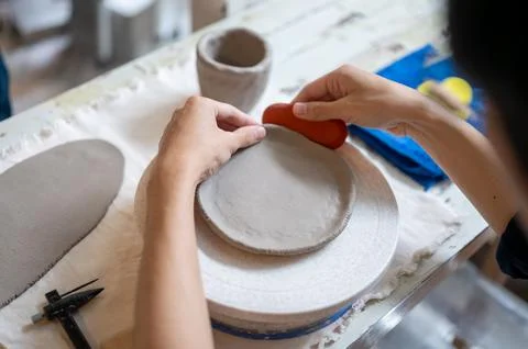 Pottery artist using a throwing tool on clay to make a circle at working ta.. Stock Photos