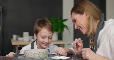 Pottery class workshop. Mother teaches her happy son drawing on clay bowl in Video stock 155992969
