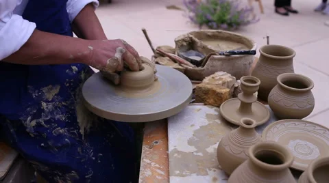 Pottery maker uses a kick wheel to hand mold a pot from clay Stock Footage 54152894