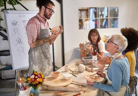 Pottery making workshop . group of people painting pot with brushes. Creati.. Stock Photos