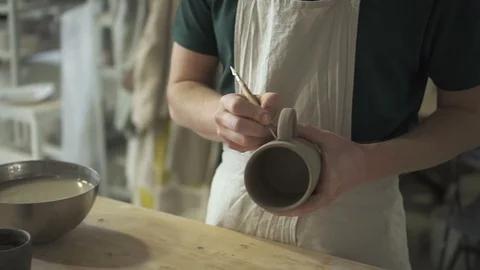 On pottery master makes notes for attaching the handle to the cup. Stock Footage 90131893