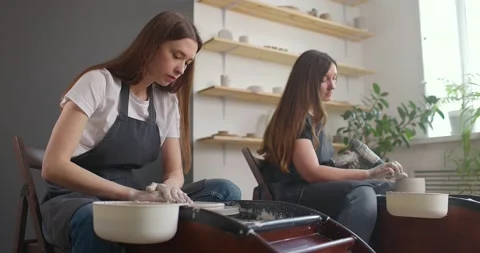Pottery studio concept. Two young woman using pottery wheel, handmade ceramics Stock Footage 155357951