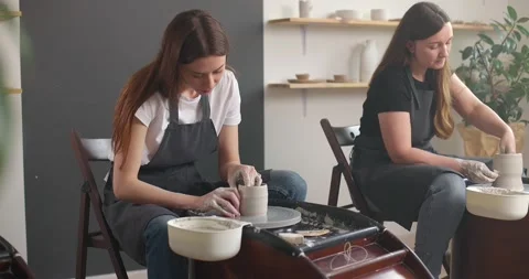 Pottery studio concept. Two young woman using pottery wheel, handmade ceramics Stock Footage 155357979