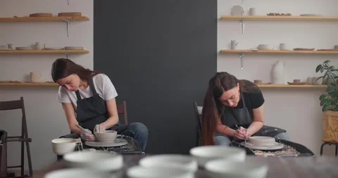 Pottery studio concept. Two young woman using pottery wheel, handmade ceramics Stock Footage 155412498