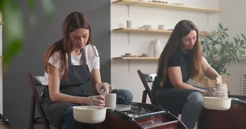 Pottery studio concept. Two young woman using pottery wheel, handmade ceramics Stock Footage 155463066