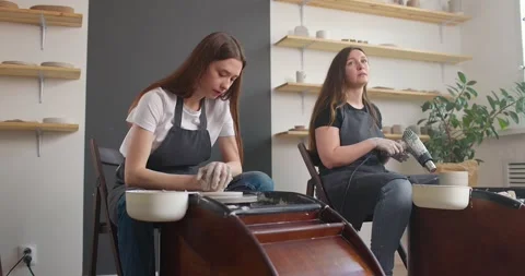 Pottery studio concept. Two young woman using pottery wheel, handmade ceramics Stock Footage 155758895
