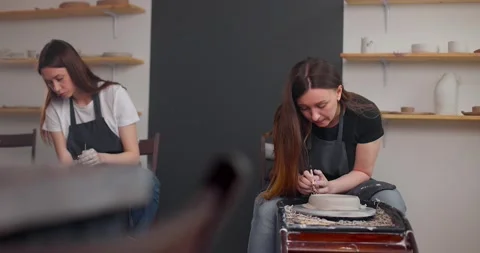 Pottery studio concept. Two young woman using pottery wheel, handmade ceramics Stock Footage 160478381