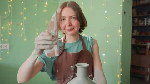 Pottery workshop white woman applying glaze and wiping vase with sponge Stock Footage 337364065