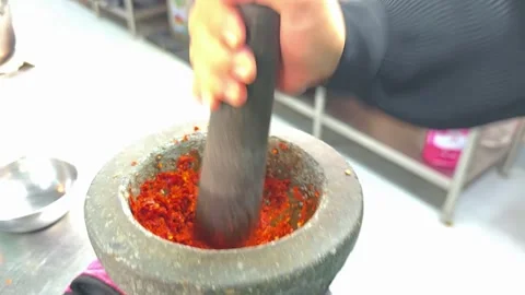 Pounding red chili paste in a stone mortar. Stock Footage 342393057