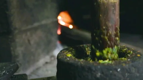 Pounding Spices and Herbs in Stone Mortar with Ancient Cooking Stove Background  Stock Footage 150907599