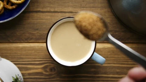 Pour cane sugar from spoon into cup of coffee with milk Video stock 106145441
