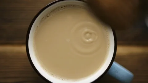 Pour cane sugar from spoon into cup of coffee with milk Vídeo Stock 106145567