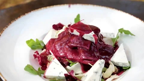 Pour cherry sauce over blue cheese salad with arugula and tongue on a white Vídeo Stock 320775190