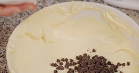 Pour chocolate chips into the dough to prepare the typical dessert Stock Footage 129154099