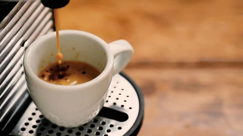 Pour coffee with coffee maker in a white cup on a wooden table in the kitchen at Stockbeeldmateriaal 74107385