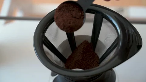 Pour coffee powder into a reusable coffee filter with a teaspoon Stock Footage 132282192