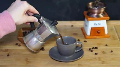 Pour a cup of coffee from moka coffee maker, steam from coffee Stock Footage 104748631